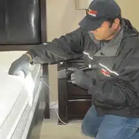 Bed bug inspection technician checking a mattress and bed frame for signs of infestation in Kansas City, KS