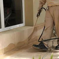 General pest control technician spraying exterior perimeter around a home in Kansas City, KS